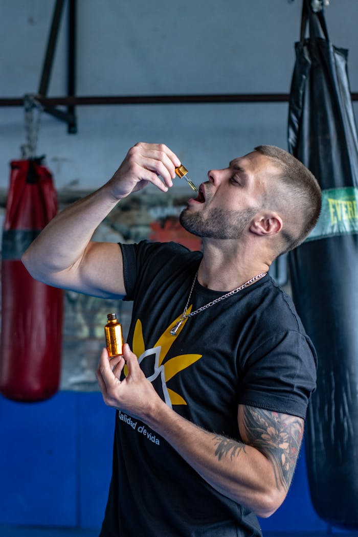 services-02 Athletic man in gym holds CBD oil, emphasizing fitness and wellness.