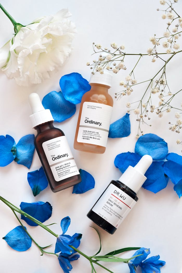gallery-6 Elegant skincare arrangement with serums and blue petals for beauty promotion.