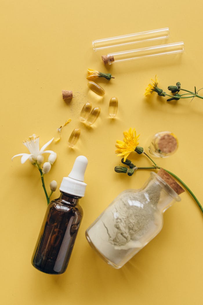 hero-img-02 Glass bottles with herbs and capsules on a bright yellow surface for wellness concept.