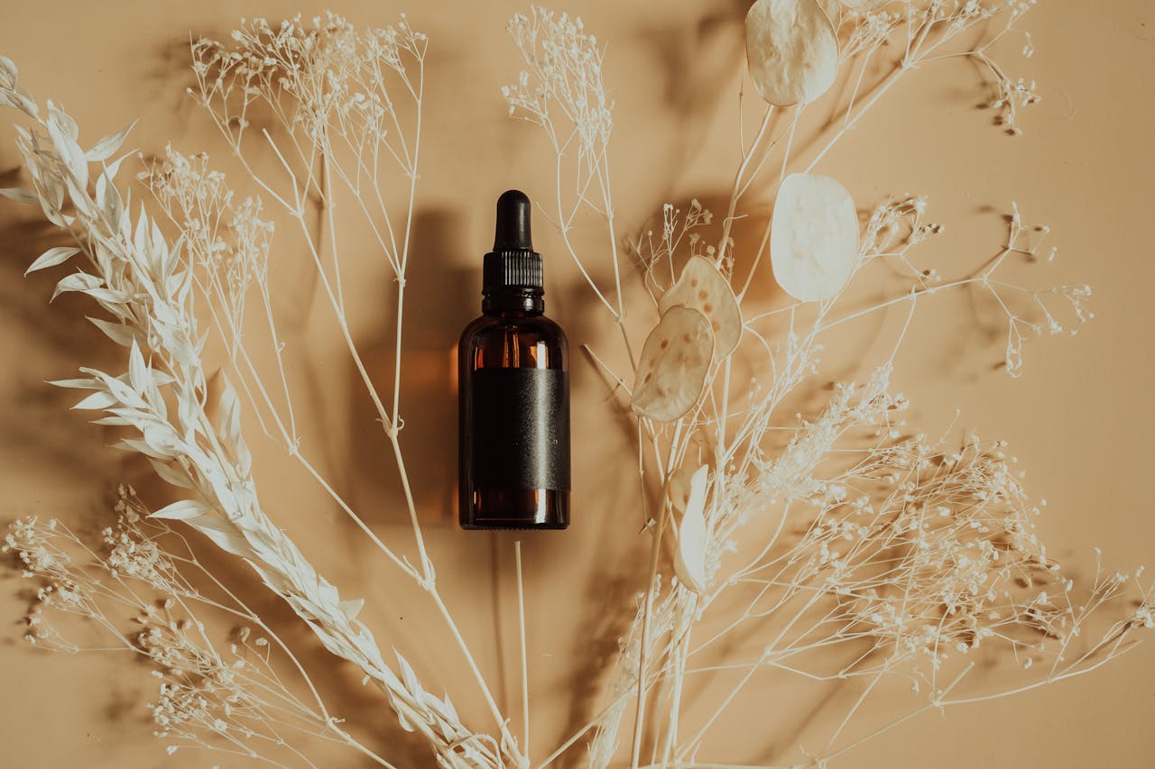 gallery-5 Flat lay of a dropper bottle for essential oils or serums surrounded by dried plants.